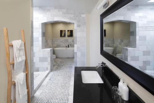 a bathroom with a tub and a sink and a mirror at Rockhouse Suites in Healdsburg