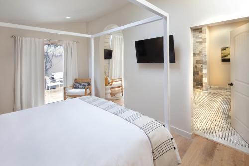 a bedroom with a white bed and a television at Rockhouse Suites in Healdsburg