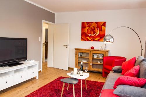 a living room with a red couch and a flat screen tv at Haus Burgfee - Obere Etage in Cochem