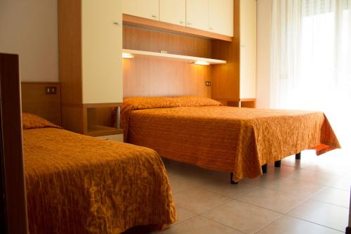 - une chambre d'hôtel avec 2 lits et des couvertures orange dans l'établissement Hotel Kennedy, à Caorle
