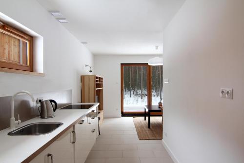 a white kitchen with a sink and a table at Osada Osjaków in Osjaków