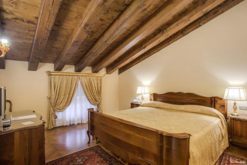 ein Schlafzimmer mit einem großen Bett und Holzdecken in der Unterkunft Villa Fenaroli Palace Hotel in Rezzato