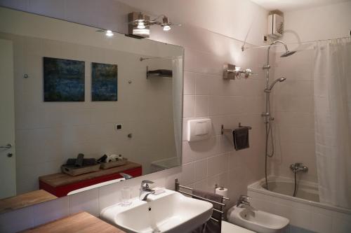 un bagno con un lavandino, uno specchio e una vasca di Casa Lorelei a Sestri Levante