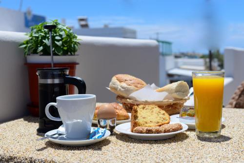a table with a breakfast of muffins and orange juice at Naxos Petite Studios in Agios Prokopios