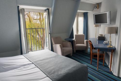 ein Hotelzimmer mit einem Bett, einem Schreibtisch und einem Fenster in der Unterkunft Die Port van Cleve in Enkhuizen