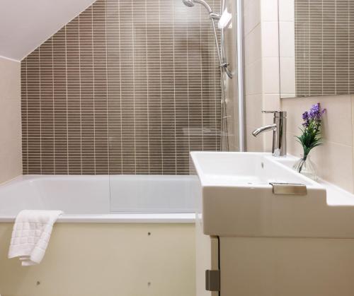 a white bathroom with a sink and a bath tub at Ravenhill House in Belfast
