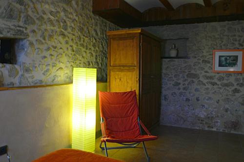 a room with a red chair and a lamp at Mas Ca La Coixa in Tortellá