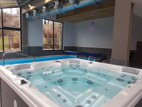 a jacuzzi tub in a room with windows at Logis SPA Hotel Restaurant De La Poste in Tence