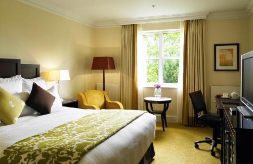 a hotel room with a bed and a desk and a window at Sprowston Manor Hotel, Golf & Country Club in Norwich