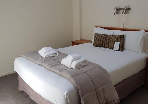 a bedroom with a large white bed with towels on it at Courtenay Village in Wellington