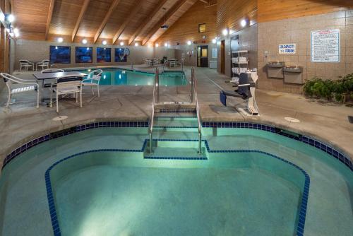 a large swimming pool with a table and chairs in a building at AmericInn by Wyndham Madison South in Madison