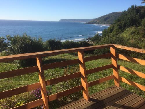 a wooden fence with the ocean in the background at Cabañas La Misión in Niebla