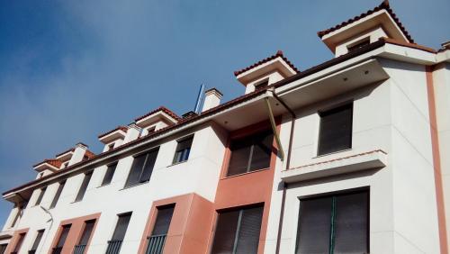 a white building with black windows and a blue sky at Norte Sueve in Colunga