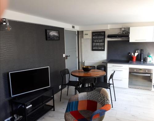 a kitchen with a table and a tv in a room at Le cosy plage in Ouistreham