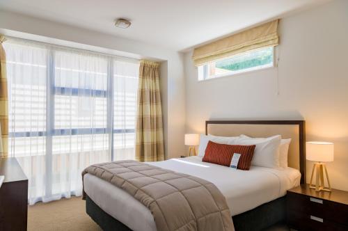 a bedroom with a bed and a large window at Boulcott Suites in Wellington