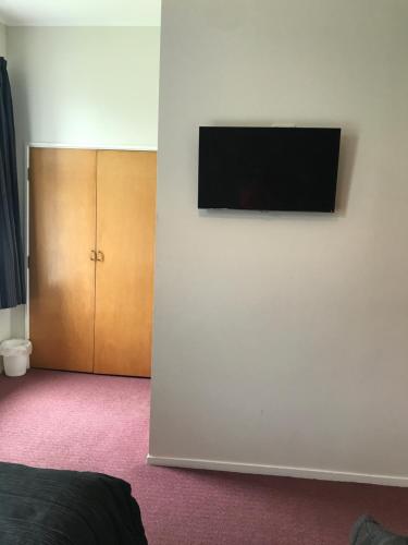 a flat screen tv on the wall of a bedroom at Criterion Club Hotel in Alexandra