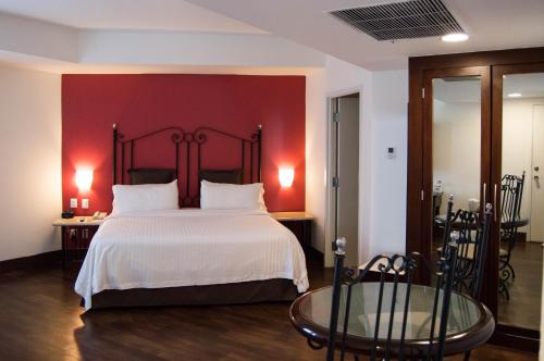 a bedroom with a large bed with a red wall at Holiday Inn Hotel & Suites Centro Historico by IHG in Guadalajara