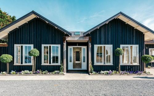 a black house with white windows and a door at The Lodge at Mudbrick in Oneroa