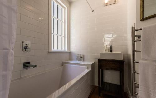 a white bathroom with a tub and a sink at Circular Bay in Awaroa