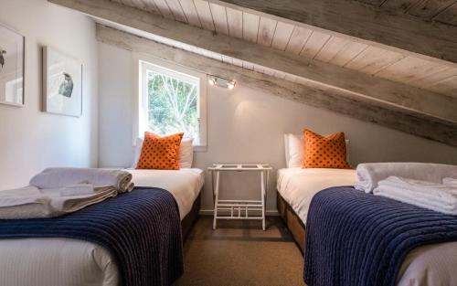 2 camas individuales en una habitación con ventana en Circular Bay en Awaroa