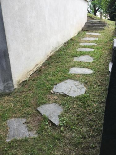 a path with stepping stones in the grass next to a wall at Casa Parentela in Ligornetto