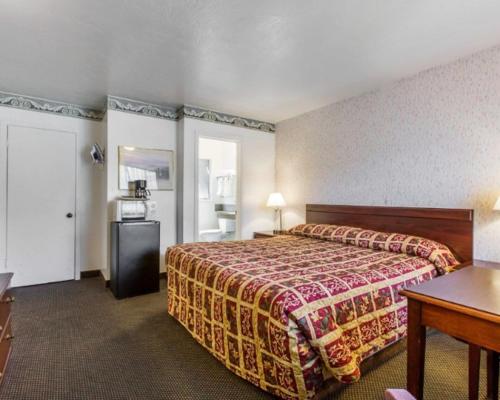 Cette chambre comprend un grand lit et une table. dans l'établissement Monterey Fairgrounds Inn, à Monterey