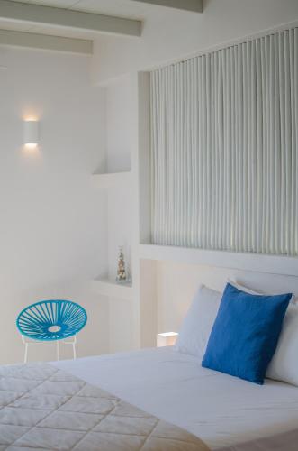 a bedroom with a large white bed with blue pillows at Hotel Katerina in Mylopotas