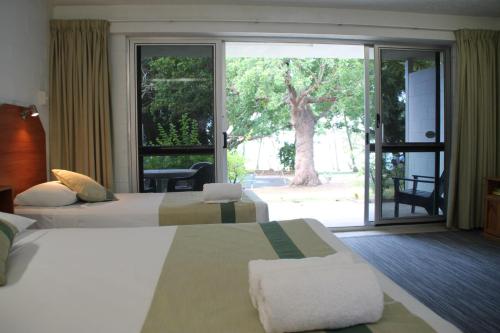 a hotel room with two beds and a sliding glass door at Whitehaven Beachfront Holiday Units in Airlie Beach