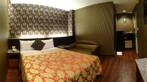 a hotel room with a bed and a chair at Klai Hotel in Kaohsiung