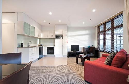 a living room with a red couch and a kitchen at Quest Canberra in Canberra