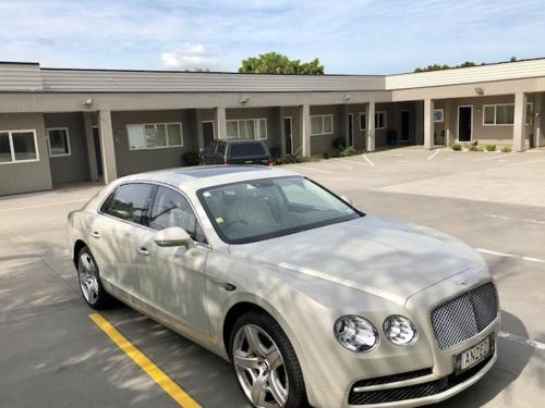 a silver car parked in a parking lot in front of a building at Phoenix Palm Motel in Auckland
