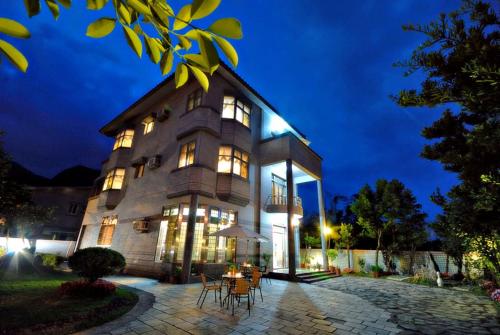 a building with a table and chairs in front of it at Yun Siang Ju Homestay in Jiaoxi