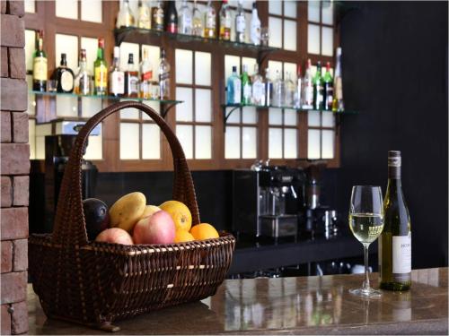 a basket of fruit on a counter with a glass of wine at Manila Lotus Hotel in Manila