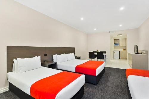 a hotel room with two beds and a television at Quality Hotel Manor in Mitcham