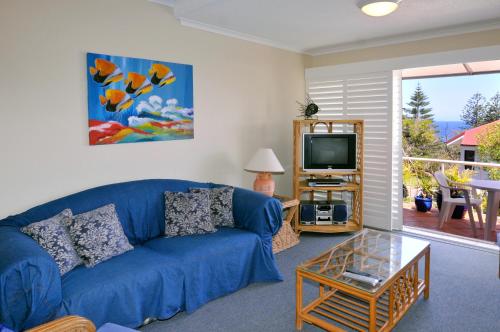 a living room with a blue couch and a tv at Bright & comfortable in quiet location in Sunshine Beach