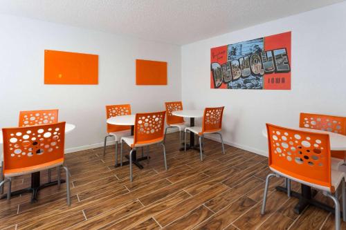 a dining room with orange chairs and tables at Super 8 by Wyndham Dubuque in Dubuque