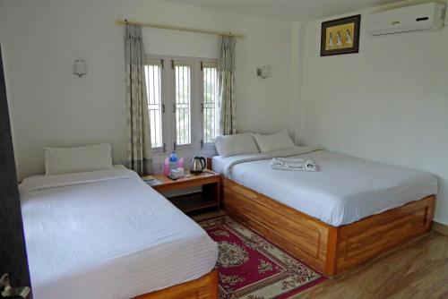 索拉哈的住宿－Tharu Mahal，客房设有两张床、一张桌子和一个窗户。