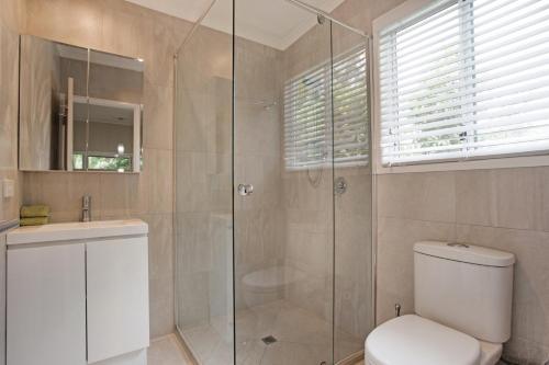 a bathroom with a shower and a toilet and a sink at Beach Cottage on Cassia Avenue, Central Coolum Beach in Coolum Beach