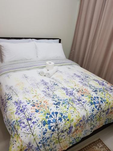 a bed with a flowered comforter with a cup on it at The Perfect Getaway in Tagaytay