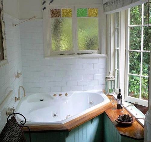 een badkamer met een bad en 2 ramen bij Lemon Tree Cottage in Leura