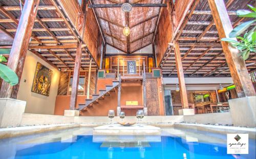 an indoor pool in a building with wooden ceilings at Apalagi Villas in Gili Air