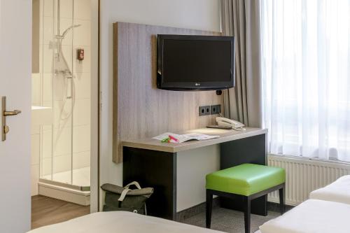 a hotel room with a television and a green stool at ibis Styles Halle in Halle an der Saale