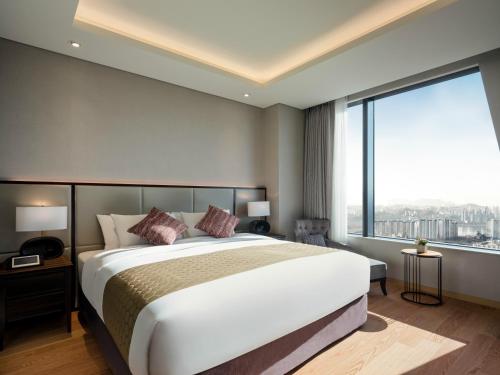 a bedroom with a large bed and a large window at Grand Mercure Ambassador Hotel and Residences Seoul Yongsan in Seoul