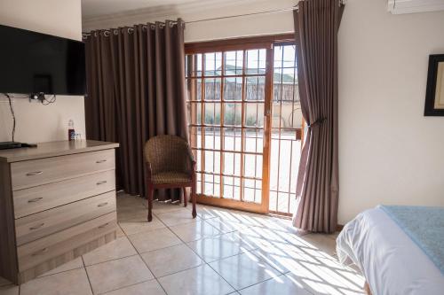a bedroom with a bed and a dresser and a window at President Lodge in Edenvale