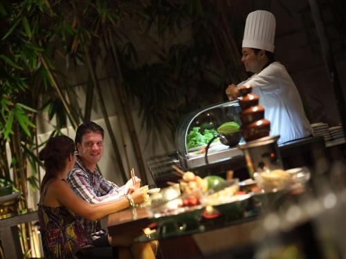 a man and a woman sitting at a table with a chef at Puri Santrian Beach Resort And Spa in Sanur