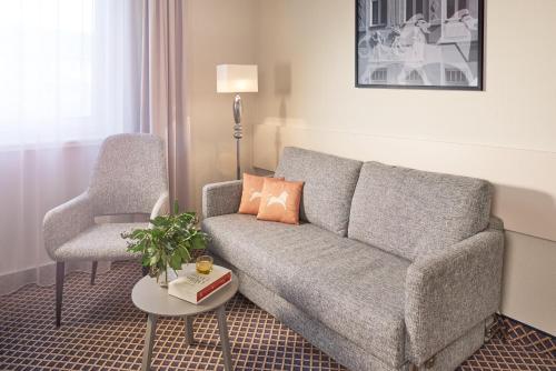 a living room with a couch and a chair at Best Western Hotel Leipzig City Centre in Leipzig
