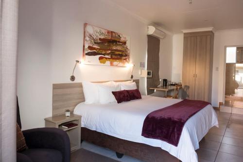 a hotel room with a bed and a chair at President Lodge in Edenvale