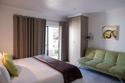 a bedroom with a bed and a couch and a window at President Lodge in Edenvale