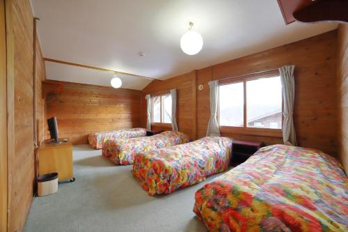 a room with three beds and a tv in it at Yado Brodiaea in Myoko