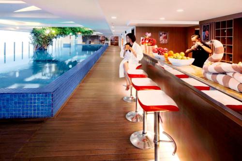 a swimming pool with people sitting at a bar at The Alana Surabaya in Surabaya